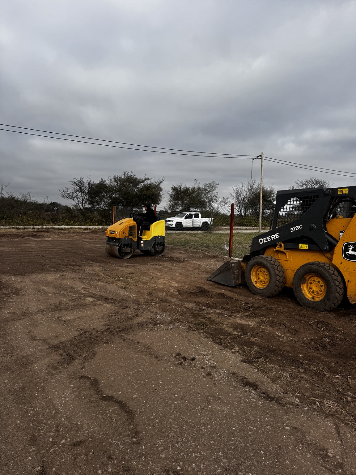 Rolo compactador y minicargadora trabajando sobre un terreno